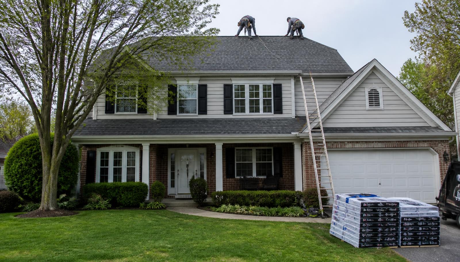 Roofing crew installing charcoal architectural shingles on a two-story Kankakee County home